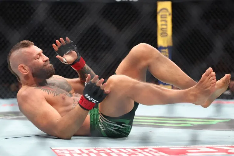 LAS VEGAS, NEVADA - JULY 11: Conor McGregor of Ireland falls after sustaining an injury on a kick in the first around against Max Holloway of the United States in their welterweight bout during UFC 329 at T-Mobile Arena on July 11, 2026 in Las Vegas, Nevada. Ian Maule/Getty Images/AFP (Photo by Ian Maule / GETTY IMAGES NORTH AMERICA / Getty Images via AFP)